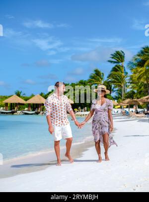 Ein paar Männer und Frauen im Urlaub auf Aruba Island Caribbean, die an einem tropischen weißen Strand spazieren gehen Stockfoto