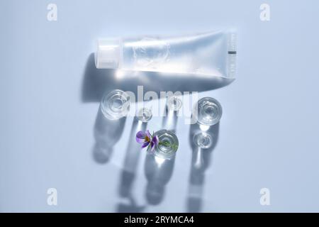 Transparente Flasche kosmetisches Gel auf blauem Hintergrund mit kleinen Flaschen Wasser. Stockfoto