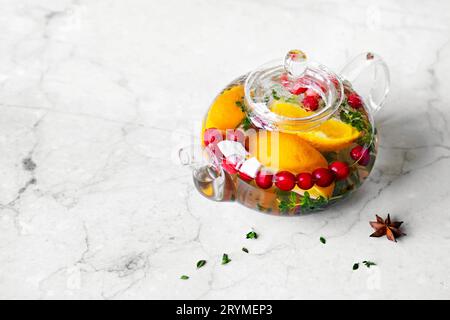 Immunitätssteigerungsgetränk. Thymian-Tee mit Preiselbeeren, Orange und Gewürzen in Glas-Teekanne auf Marmortisch Stockfoto