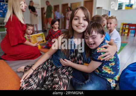 Ein Mädchen und ein Junge mit Down-Syndrom in den Armen verbringen Zeit miteinander in einer Vorschuleinrichtung Stockfoto