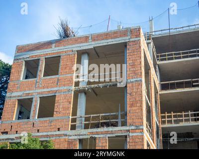 Die Bauarbeiten sind in vollem Gange. Haus aus roten Blöcken und Stahlbeton. Holzseitenteile zur Sicherheit auf Baustellen Stockfoto