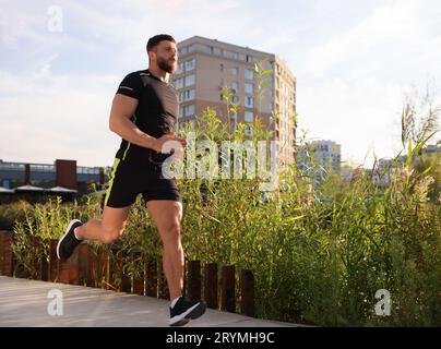 Junger Mann, der an sonnigen Tagen draußen läuft. Leerzeichen für Text Stockfoto