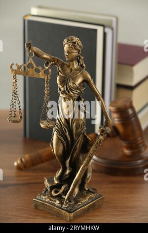 Figur der Lady Justice, Hammer und Bücher auf Holztisch im Innenbereich. Symbol der gerechten Behandlung nach dem Gesetz Stockfoto