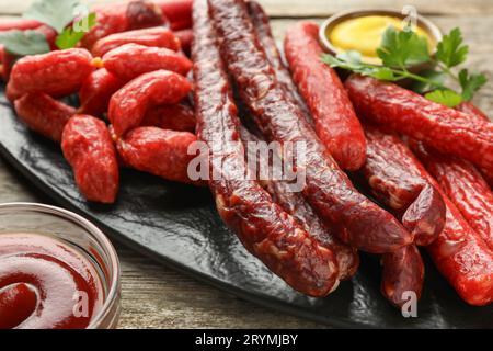 Dünne, trocken geräucherte Würstchen, serviert auf Holztisch, Nahaufnahme Stockfoto