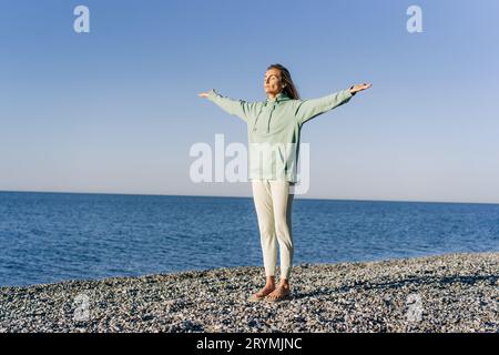 Frau, die Energie-Yoga praktiziert, am Meer, während sie auf Brettern mit Nägeln steht. Stockfoto