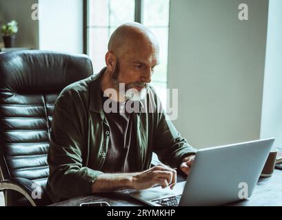 Der Mann konzentrierte sich zutiefst auf die Arbeit als Freiberufler. Mit unerschütterlichem Fokus und Leidenschaft taucht er in seine Aufgaben im Büro ein Stockfoto