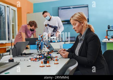 Eine Frau, die in einem Labor sitzt und Probleme löst und die Verifizierung des Roboters analysiert. Im Hintergrund sind die Kollegen t Stockfoto