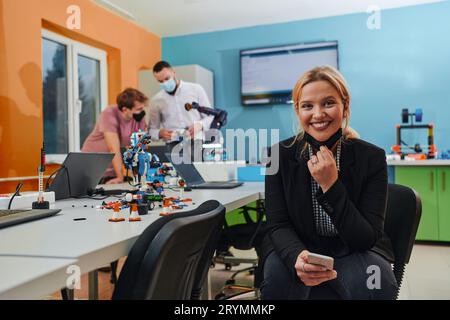 Eine Frau, die in einem Labor sitzt und Probleme löst und die Verifizierung des Roboters analysiert. Im Hintergrund sind die Kollegen t Stockfoto