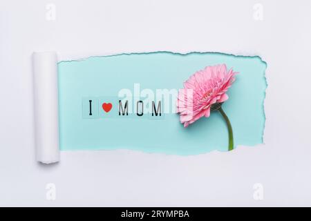 Ich liebe Mom Concept. Kreatives Layout aus I Love Mom Text und rosa Blume auf blauem Hintergrund. Einfache Papierkunst mit abgerissenem Loch Stockfoto