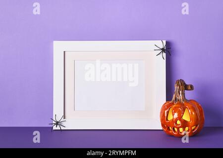 Halloween-Komposition mit Keramik Kürbisse Jack Laterne und Rahmen auf Tischwand Hintergrund. Grußkartenvorlage Stockfoto