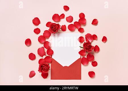 Roter Umschlag mit romantischem Liebesbrief Mockup, Rosenblüten und Blütenblättern auf rosa Hintergrund Stockfoto