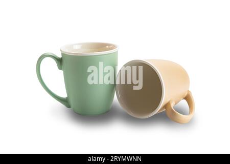 Nahaufnahme von zwei leeren Keramikkkaffeetassen braun und grün isoliert auf weißem Hintergrund. Stockfoto