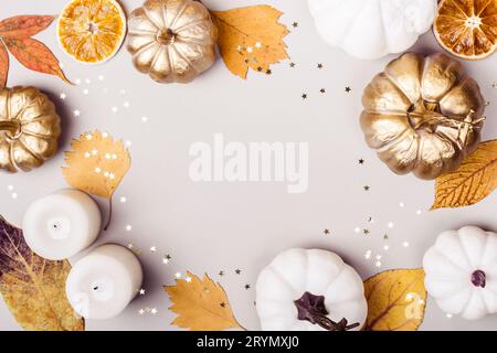 Herbst- oder Thanksgiving-Tag-Konzept. Goldener Kürbis, trockene Blätter und Kerzenrahmen auf grauem Hintergrund Stockfoto