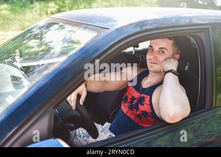 Porträt eines lächelnden jungen Mannes, der in einem Auto sitzt und in die Kamera schaut Stockfoto