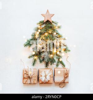 „Zero Waste Christmas“-Konzept. Weihnachtsbaum aus natürlichen Tannenzweigen mit Holzstern und Papierspitze Geschenk Stockfoto