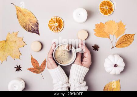 Kreative Komposition im Herbst. Weibliche Hände halten eine Tasse Kaffee mit Zimt Stockfoto