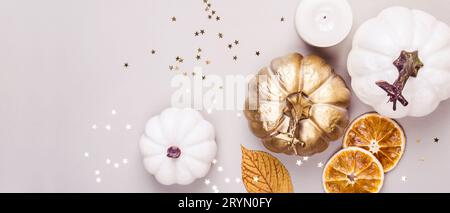 Dekorative Kürbisse, goldenes Konfetti und trockene Blätter auf grauem Hintergrund. Herbstkonzept Stockfoto