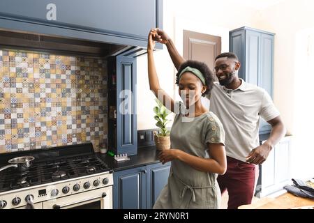 Glückliches afroamerikanisches Paar, das Spaß hat, zusammen in der Küche zu tanzen Stockfoto