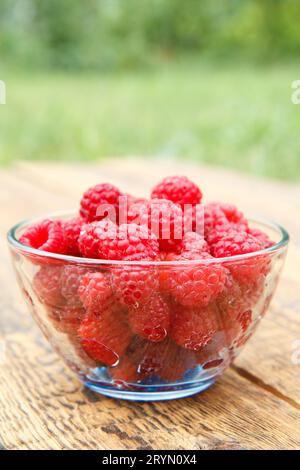 Reife Himbeeren in der Glasschale auf den Holzbrettern. Stockfoto
