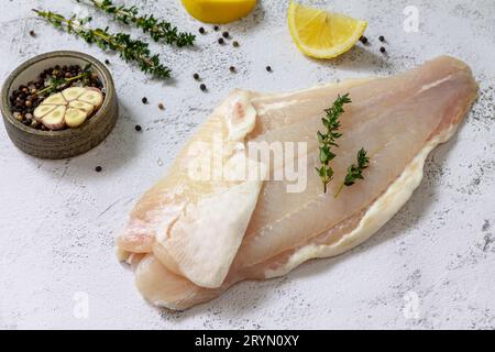 Meeresfrüchte, rohes weißes Fischfilet zum Kochen. Frisches Filet Pangasius mit Gewürzen, Zitrone und Thymian auf steinernem Hintergrund. Stockfoto