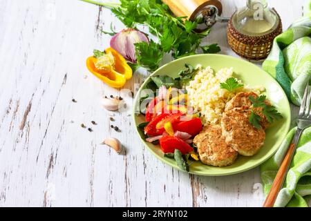Gesunde vegane Lebensmittel, Keto- oder Paläodiäten. Hausgemachte rote Fischschnitzel mit Bulgur und frischem Gemüsesalat auf einem Holztisch. Stockfoto