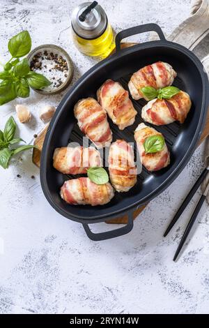 Ein festliches Gericht. Gebackenes Hähnchenfilet mit Ricotta in Speck auf einer Steinplatte. Draufsicht flach lay Hintergrund. Speicherplatz kopieren. Stockfoto