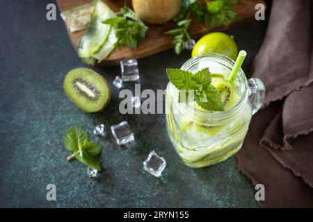 Erfrischendes Sommergetränk mit Kiwi, Gurke, Limette und Eis, Mojito oder Limonade mit Gurke auf einem dunklen Steintisch. Stockfoto