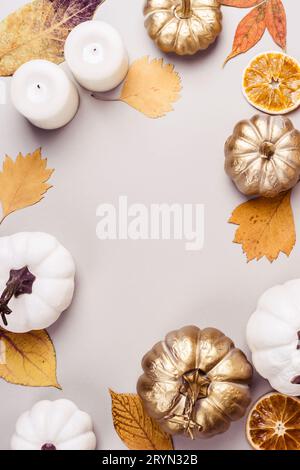 Goldener Kürbis, trockene Blätter und Kerzenrahmen auf grauem Hintergrund. Herbstferienkonzept Stockfoto