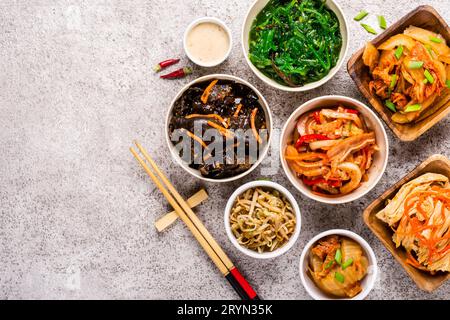 Verschiedene koreanische eingelegte Speisen und Essstäbchen auf grauem Hintergrund Stockfoto