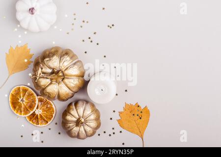 Herbstfeier-Konzept. Dekorative Kürbisse, goldenes Konfetti und trockene Blätter auf grauem Hintergrund Stockfoto