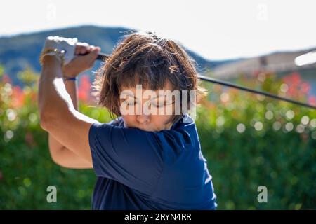 Vorderansicht einer Golferin, die an einem sonnigen Tag in der Schweiz Golf spielt Stockfoto