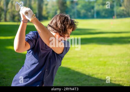 Golferin macht einen Golf Swing an einem sonnigen Tag in der Schweiz Stockfoto