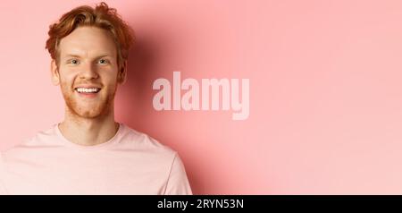 Headshot des glücklichen Rotschopf Mann mit Bart und weißen Zähnen, lächelnd aufgeregt auf Kamera, stand über rosa Hintergrund Stockfoto