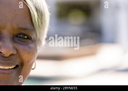 Ein halbes Porträt einer glücklichen älteren, birassischen Frau, die im sonnigen Garten lächelt, Kopierraum Stockfoto