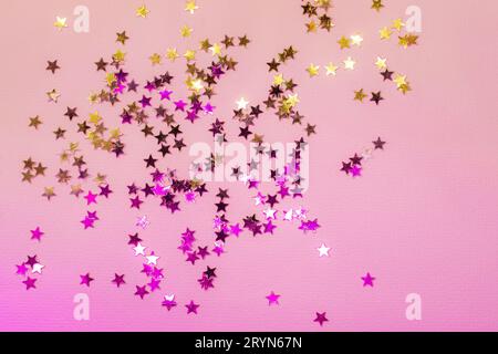 Holographische Konfetti-Sterne auf rosa Neonhintergrund Stockfoto