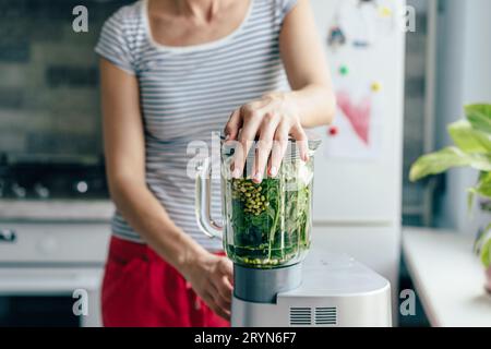 Young mahlt und mischt die Smoothie-Zutaten in einem Mixer. Gesunde Ernährung Konzept. Kochen zu Hause. Stockfoto