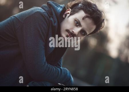 Porträt eines jungen Mannes in Kopfhörern. Zu Fuß zum Frühlingspark am Abend. Stockfoto