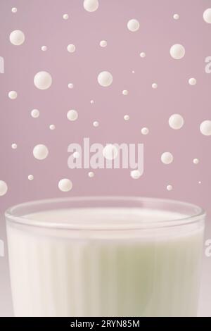 Milch in einem transparenten facettierten Glas und tropft darüber. Stockfoto
