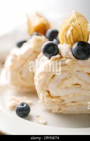 Zwei Stücke Meringue-Rolle mit Beeren auf einem Teller. Stockfoto