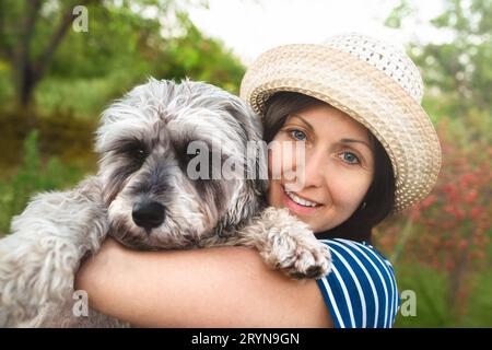 Bild einer schönen Frau mittleren Alters mit Strohhut, die beim Spaziergang im Sommerpark zur Seite schaut Stockfoto
