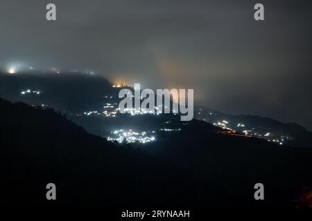 Nachtaufnahme mit darjeeling Dorf, eingebettet in die Mitte der himalaya Berge mit orange und blauen Lichtern Stockfoto