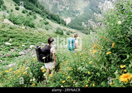 Ein Rückblick auf Wanderer mit Rucksäcken, die auf einer Bergexpedition durch das hohe Gras unterwegs sind. Stockfoto