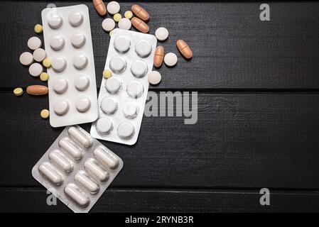 Medizinische Werkzeuge, Spritze und bunte Medikamente und Kapseln Medizin-Konzept, brauner hölzerner Hintergrund, Vorderansicht, Nahaufnahme, isoliert. Stockfoto