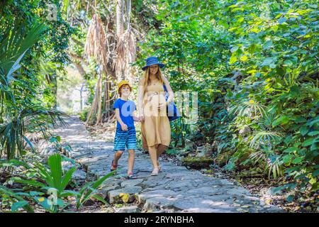 Werdende Mutter und ihr Sohn genießen einen gemütlichen Spaziergang im Park und genießen kostbare Momente inmitten der Schönheit der Natur Stockfoto