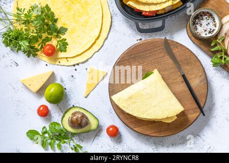 Kochprozess für Sandwiches und Zutaten. Sandwich Hühnchen mexikanische Maistortillas mit Avocado, Rucola und Käse auf einem Grau Stockfoto