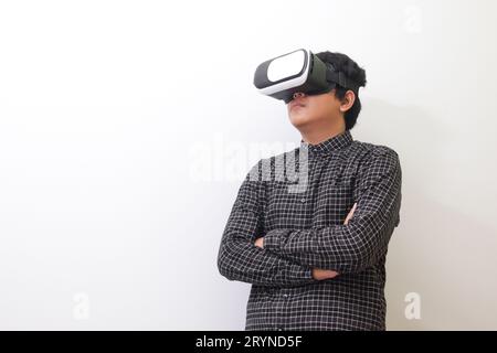 Porträt eines asiatischen Mannes in einem schwarzen karierten Hemd mit Virtual Reality (VR)-Brille und gedrückten Armen. Isoliertes Bild auf weißem Hintergrund Stockfoto