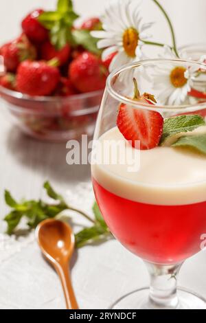 Kirsch- und Milchgelee mit Erdbeerstück im Glas und Blumen Stockfoto