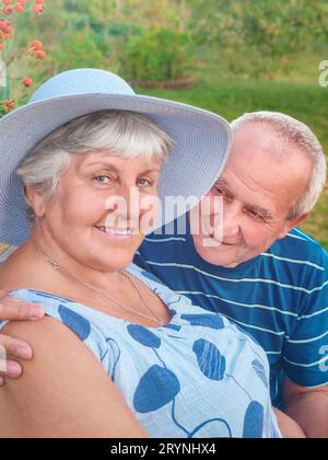 Authentische Outdoor-Aufnahme von alterndem Paar, das Spaß im Garten hat und mit Liebe gesegnet ist. Während ihres Spiels versucht man, h zu küssen Stockfoto