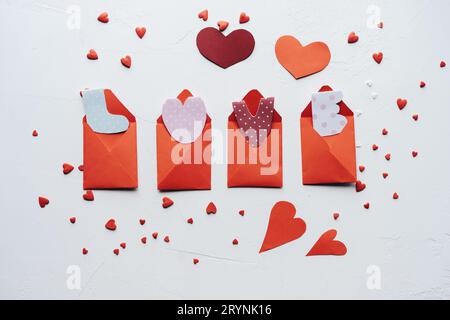 Handgeschriebene Papierbriefe LIEBEN in kleinen roten Umschlägen auf weißem Hintergrund. Festliche, flache Laie. Liebhaber und valentinstag Konzept. Stockfoto