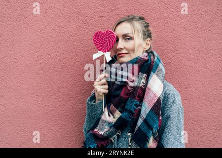 Charmante Frau mit großen herzförmigen Karamell rosa Lollipop. Stockfoto